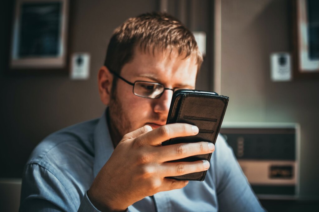 man using phone near brown wall
